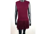 Le mannequin porte une robe rouge ornée de franges.