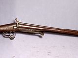 un vieux pistolet avec une crosse en bois et un étui, posé sur une surface blanche