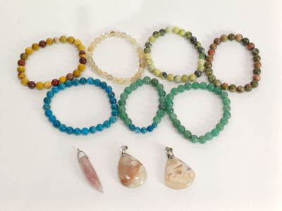 Plusieurs bracelets de différentes couleurs et formes sont disposés sur une surface blanche.