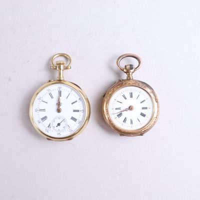two gold pocket watches sitting side by side on a white surface