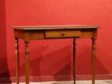 a small table with a drawer on it in front of a red wall