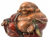 a statue of a laughing buddha sitting on top of a bell