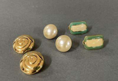 three gold and green buttons and two pearls on a table