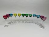 six verres à vin colorés alignés sur une surface blanche