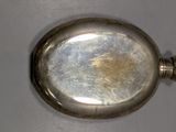 a silver pocket watch on a table with a white background