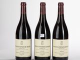 trois bouteilles de vin rouge sont alignées sur une surface blanche