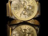 a gold watch with roman numerals on a black surface