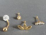 three pairs of ear piercings on a gray surface