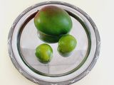 three limes on a silver plate on a white table