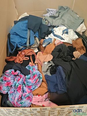une boîte en carton remplie de vêtements, ainsi que des vêtements éparpillés sur le sol