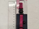 a close up of a pink cat collar with a ruler in front of it