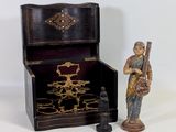 une figurine représentant un homme tenant un instrument de musique à côté d'une boîte