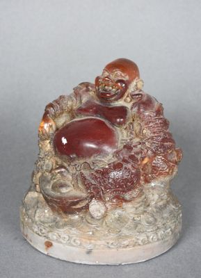 une petite figurine représentant un Bouddha souriant assis sur un rocher