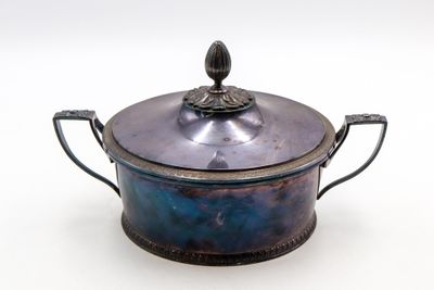 une petite casserole en métal avec un couvercle, posée sur une surface blanche