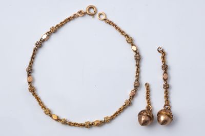 un gros plan d'un collier et d'un bracelet ornés de clochettes, posés sur une surface blanche
