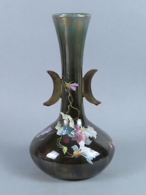un vase noir orné de fleurs, posé sur une table