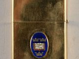 une image représentant un briquet doré orné d'un emblème bleu