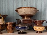 de nombreux vases et bols de toutes sortes posés sur une étagère