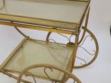 an antique brass bar cart with glass shelves and wheels