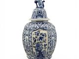 blue and white vase with a cat on top of it on a white surface