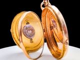 a close up of a gold pocket watch on a white plate