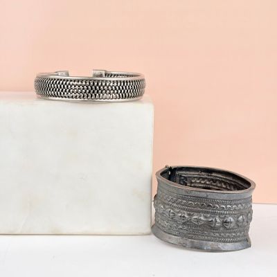 deux bracelets en argent posés sur un bloc de marbre blanc