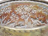a close up of a metal bowl with a tree design on it