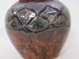 a brown vase with a lid sitting on a white surface