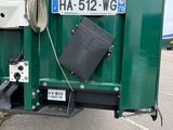 a green container that has a black trash can inside of it