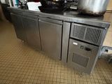 un plan de travail en acier inoxydable sur lequel sont posés des casseroles et des poêles, dans une cuisine professionnelle
