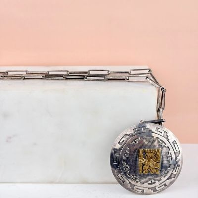 un porte-monnaie en argent muni d'une chaîne, posé sur une table