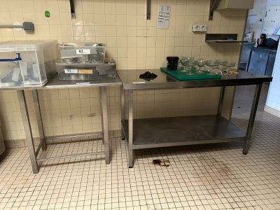 two stainless steel tables in a kitchen with a sink