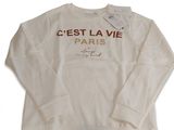 Le pull est blanc et comporte un imprimé doré.