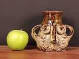 a vase with a face on it next to a green apple