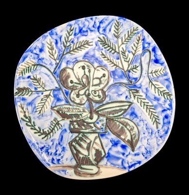 une assiette bleue et blanche sur laquelle est représenté un vase de fleurs