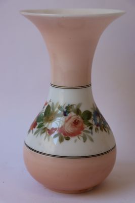 un vase blanc avec des fleurs roses sur une table