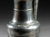 une image représentant un vase en argent muni d'une anse, posé sur une table