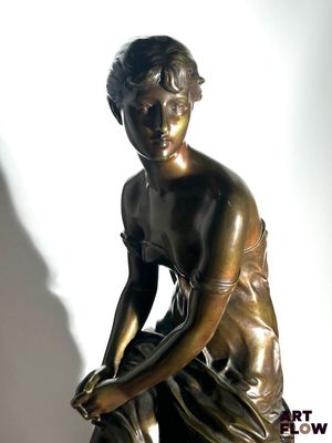 bronze statue of a boy sitting on a rock with his hands on his knees
