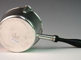 a silver pot with a black handle on a white table