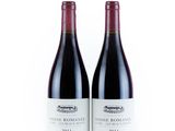 two bottles of red wine sitting next to each other on a white surface