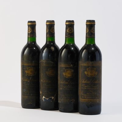 quatre bouteilles de vin sont alignées sur une surface blanche