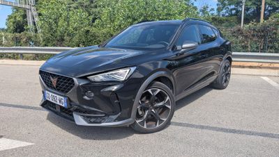 une voiture noire garée sur un parking près des arbres