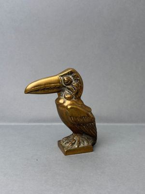 brass statue of a bird on a stand on a gray background