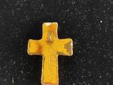 yellow metal cross on black cloth with a small hole in the middle