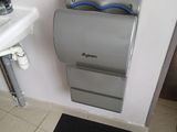 une salle de bains équipée de toilettes, d'un lavabo et d'un distributeur de papier accroché au mur