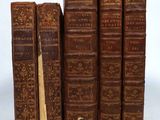 several old books sitting on top of each other on a white surface