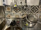 Les casseroles et les poêles sont posées sur un plan de travail de cuisine équipé d'un évier.
