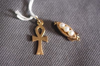 gold ankht and pearl pendants on a gray cloth