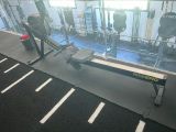 une photo d'une salle de sport avec une rangée d'appareils