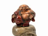 statue of a laughing buddha sitting on a rock on a white background
